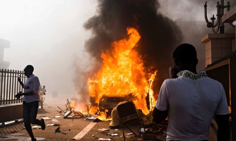A car burns outside the parliament building in Burkina Faso